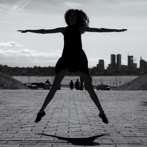 A dynamic black and white silhouette of a woman jumping with arms outstretched in Tallinn, Estonia.