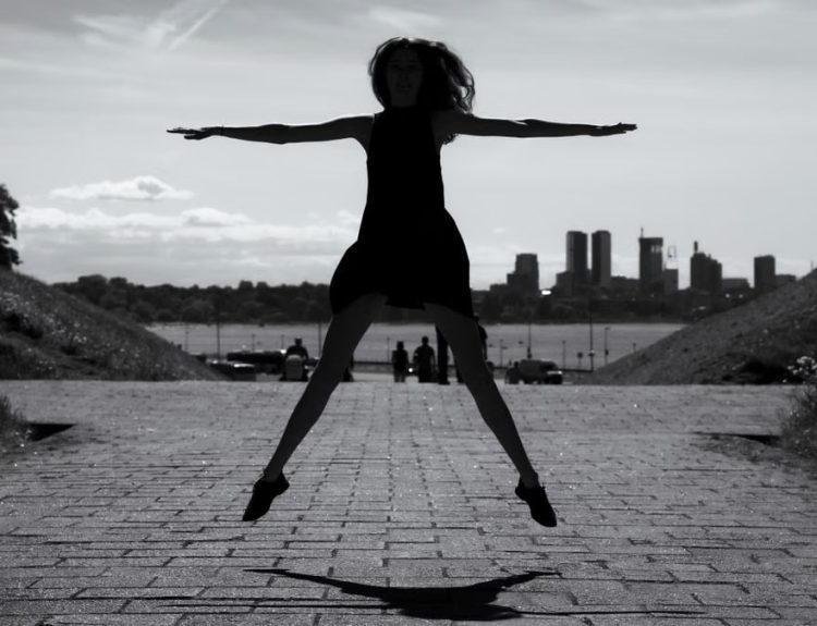 A dynamic black and white silhouette of a woman jumping with arms outstretched in Tallinn, Estonia.