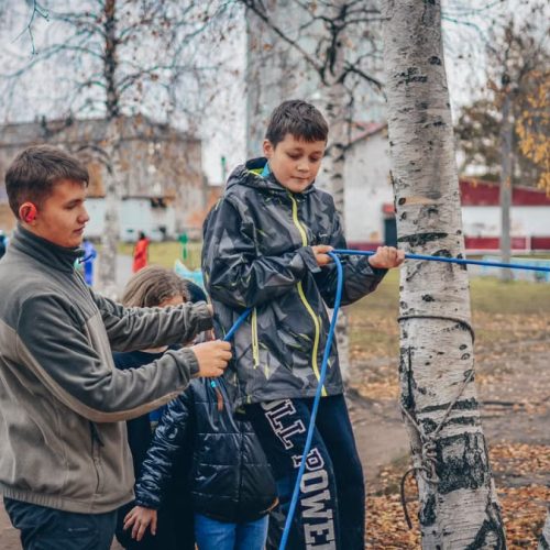 Kids enjoying an outdoor rope activity among birch trees during fall.