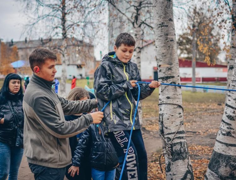 Kids enjoying an outdoor rope activity among birch trees during fall.