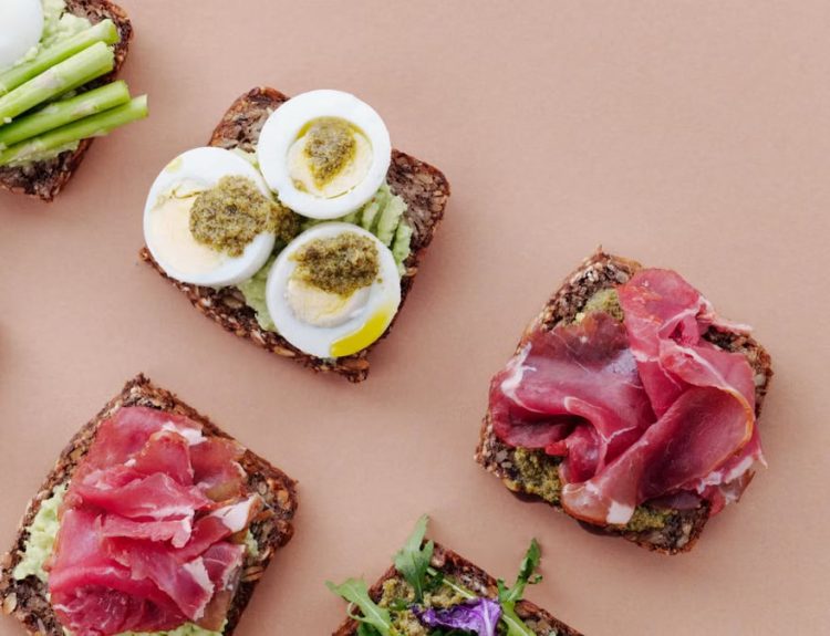 Delicious open-faced sandwiches with gourmet toppings including eggs, ham, and asparagus on rustic bread.